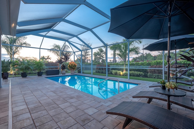 pool at dusk featuring a patio area and a lanai