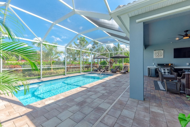 view of swimming pool featuring a patio, ceiling fan, and glass enclosure