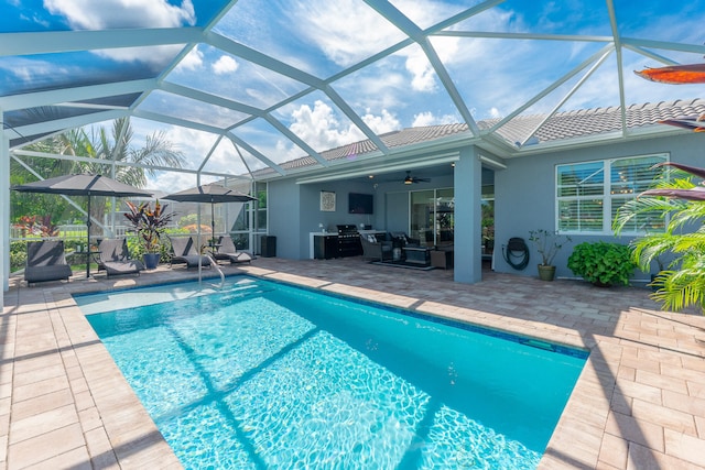 view of swimming pool featuring a patio, glass enclosure, and ceiling fan