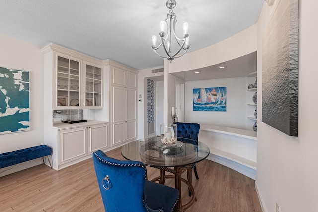 dining room with light hardwood / wood-style flooring, a textured ceiling, and a chandelier