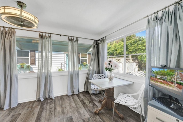 sunroom / solarium featuring baseboards, wood finished floors, and plenty of natural light