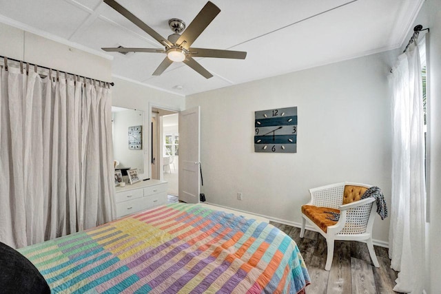 bedroom with multiple windows, wood finished floors, and baseboards