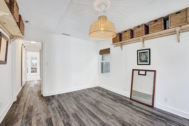 spare room featuring an inviting chandelier, visible vents, wood finished floors, and baseboards