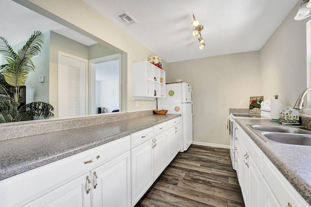 kitchen featuring a sink, visible vents, white appliances, white cabinets, and dark wood finished floors