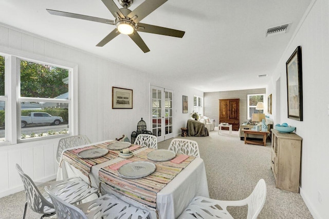 dining space with ceiling fan and light colored carpet