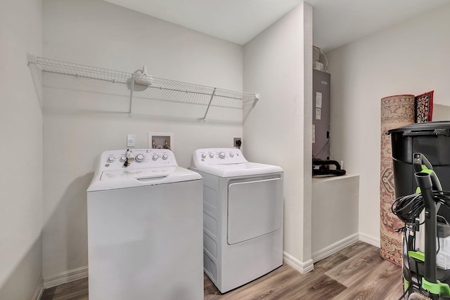 laundry area featuring hardwood / wood-style flooring, washing machine and dryer, and water heater