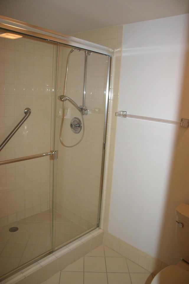 bathroom featuring toilet, tile patterned floors, and walk in shower