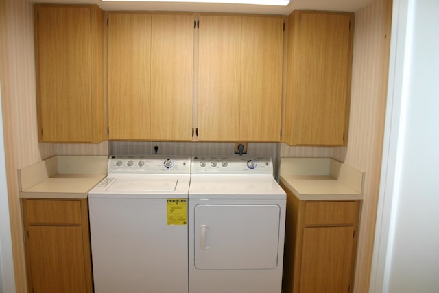 clothes washing area with cabinets and separate washer and dryer