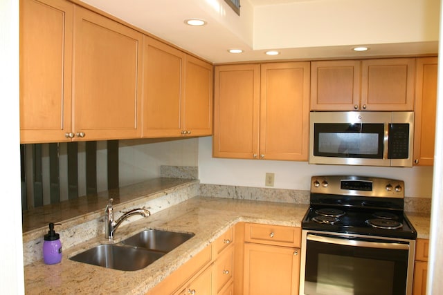 kitchen with light stone counters, sink, and appliances with stainless steel finishes