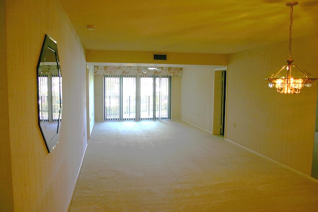 carpeted spare room with a notable chandelier