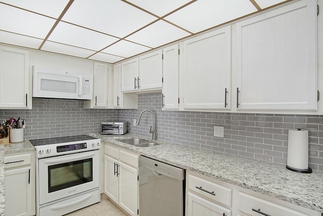 kitchen featuring white appliances, sink, white cabinetry, decorative backsplash, and light tile patterned floors