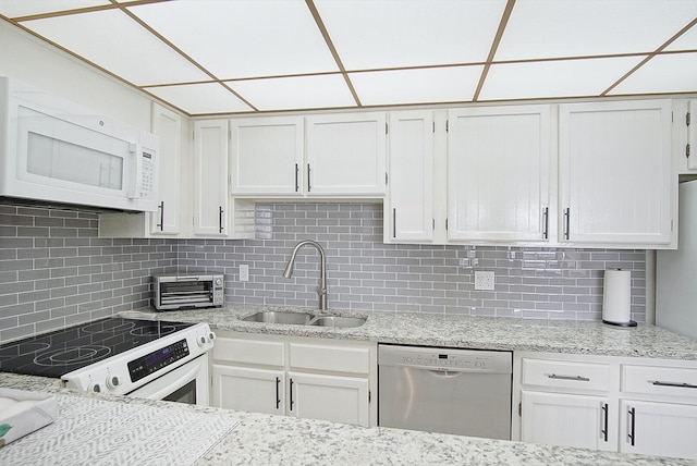 kitchen with white appliances, white cabinetry, sink, and decorative backsplash