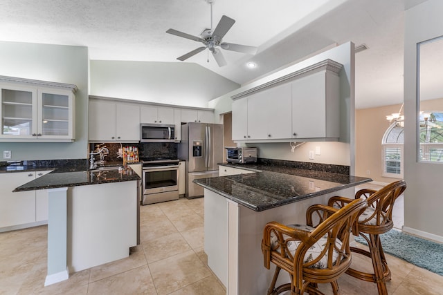 kitchen featuring a breakfast bar, vaulted ceiling, kitchen peninsula, and stainless steel appliances