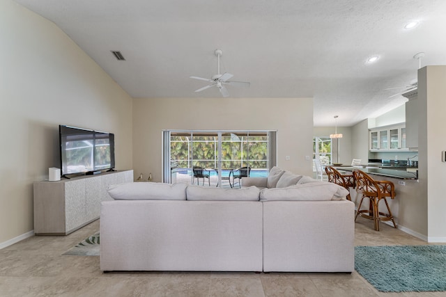 living room featuring a textured ceiling, light tile patterned floors, ceiling fan with notable chandelier, and vaulted ceiling