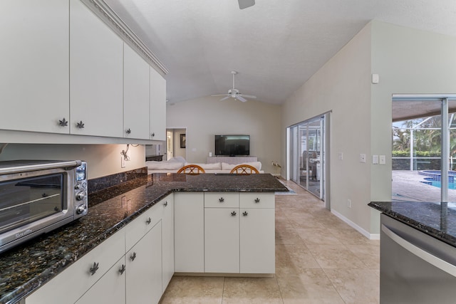 kitchen with white cabinetry, dark stone counters, vaulted ceiling, and kitchen peninsula