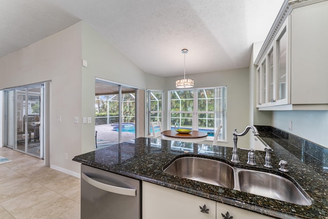 kitchen with white cabinets, hanging light fixtures, dark stone countertops, dishwasher, and sink