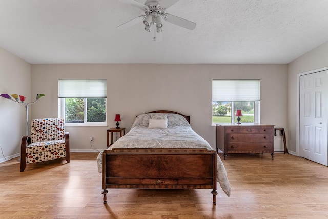 bedroom featuring ceiling fan, a textured ceiling, and light wood-type flooring