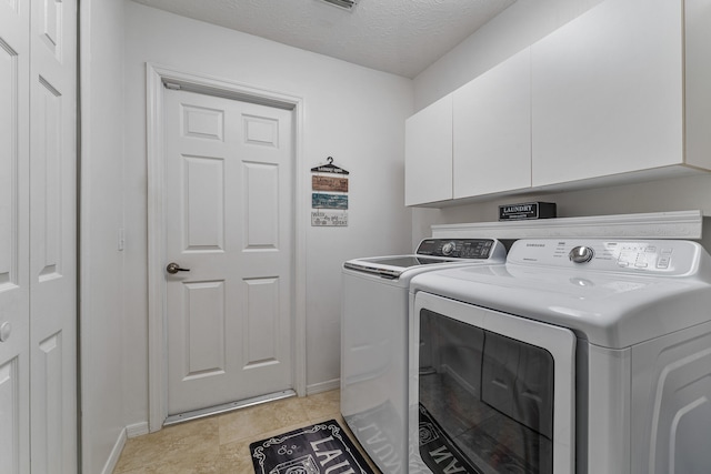 washroom featuring light tile patterned floors, a textured ceiling, cabinets, and separate washer and dryer