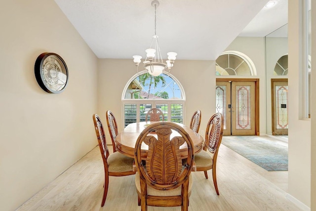 dining area with light hardwood / wood-style floors, a chandelier, and a high ceiling