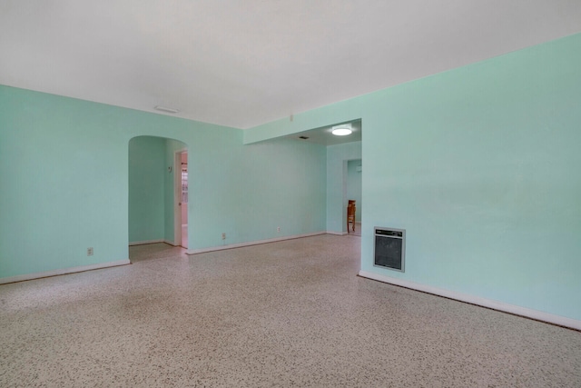 unfurnished room with heating unit and a fireplace