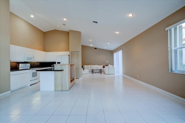 kitchen featuring white appliances, white cabinets, sink, vaulted ceiling, and light tile patterned floors