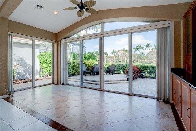 doorway featuring light tile patterned floors, vaulted ceiling, and plenty of natural light