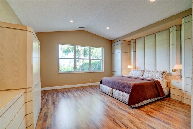 bedroom with hardwood / wood-style flooring, a textured ceiling, and vaulted ceiling