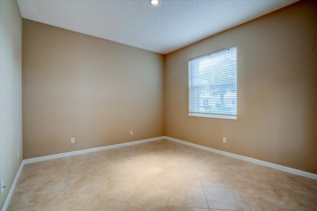 tiled empty room featuring a textured ceiling