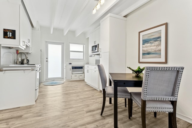 dining room with beam ceiling, sink, heating unit, and light wood-type flooring