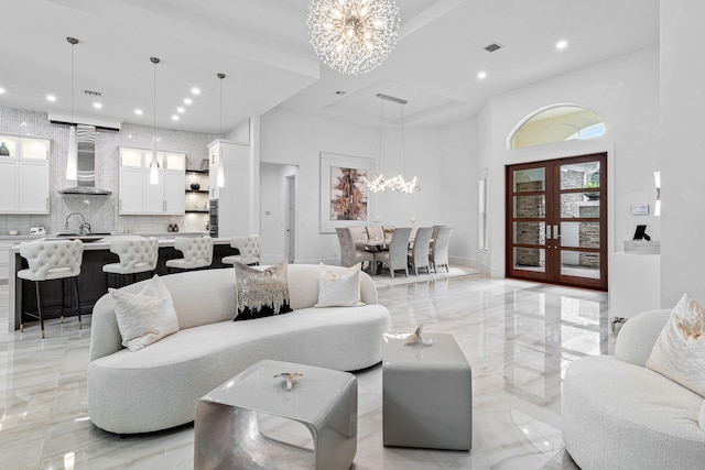 living room with french doors, a notable chandelier, sink, and a high ceiling