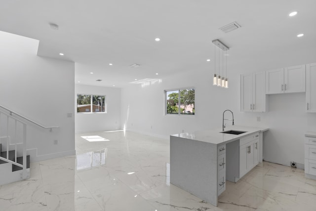 kitchen featuring white cabinets, kitchen peninsula, a wealth of natural light, and decorative light fixtures