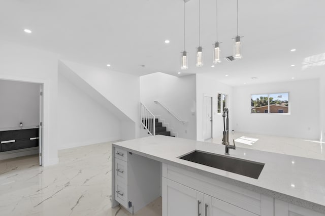 kitchen with white cabinets, sink, decorative light fixtures, and light stone counters