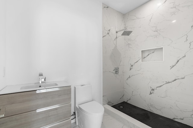 bathroom featuring a tile shower, vanity, and toilet