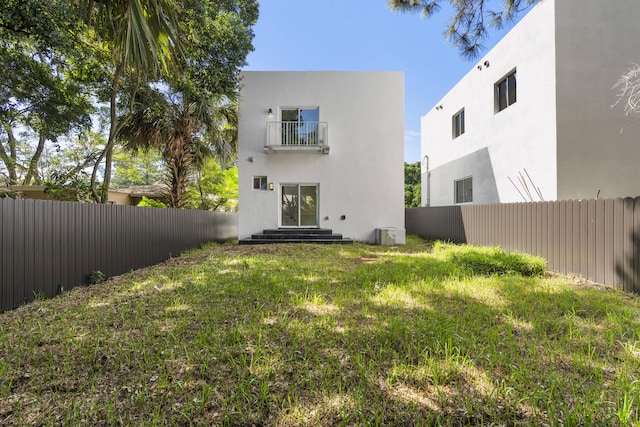 back of house with a lawn and a balcony