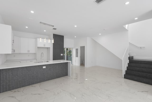 kitchen with white cabinets, kitchen peninsula, hanging light fixtures, and sink