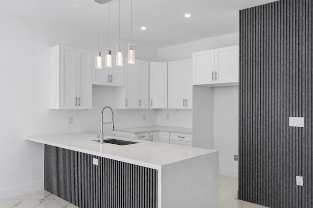 kitchen featuring pendant lighting, kitchen peninsula, white cabinetry, and sink