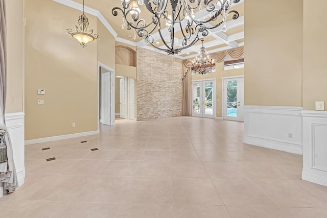 tiled spare room with french doors, coffered ceiling, a high ceiling, crown molding, and a notable chandelier