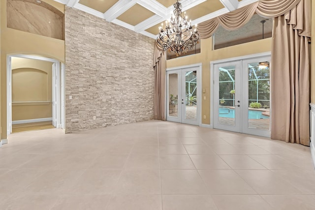 spare room featuring a chandelier, crown molding, light tile patterned flooring, a high ceiling, and french doors