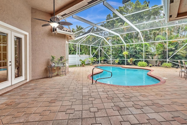 view of swimming pool with a patio, ceiling fan, and glass enclosure