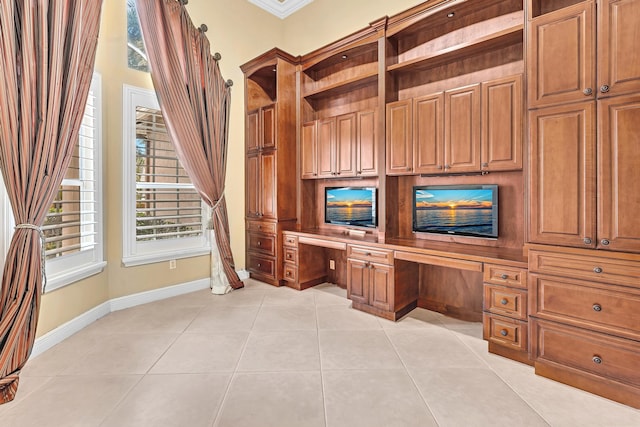 unfurnished office featuring built in desk, ornamental molding, and light tile patterned floors