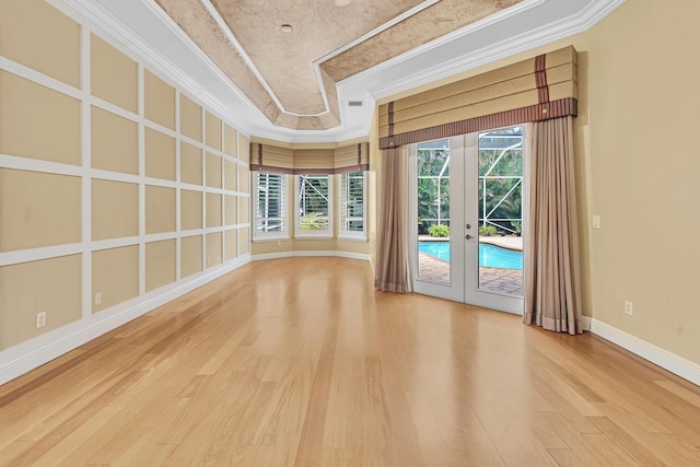 unfurnished room featuring hardwood / wood-style floors, crown molding, a healthy amount of sunlight, and french doors