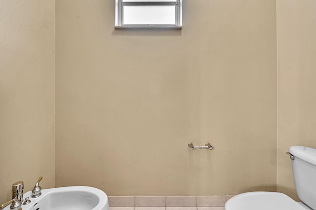 bathroom featuring toilet, sink, a bidet, and tile patterned flooring