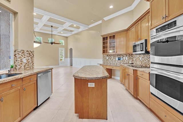 kitchen with tasteful backsplash, a kitchen island, light stone counters, stainless steel appliances, and crown molding