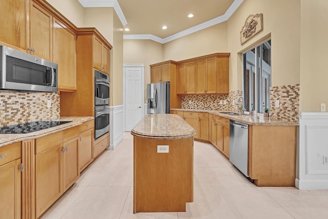 kitchen featuring ornamental molding, a center island, appliances with stainless steel finishes, and light stone counters