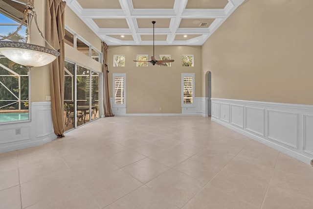 tiled spare room with coffered ceiling, a healthy amount of sunlight, and beamed ceiling