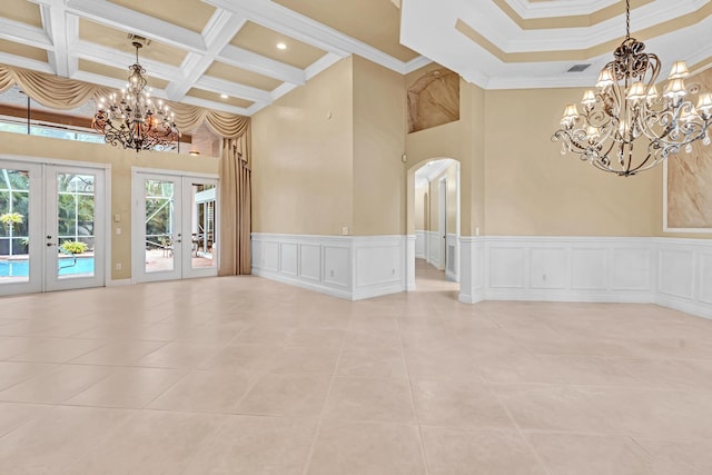 tiled spare room with coffered ceiling, french doors, a high ceiling, crown molding, and a chandelier