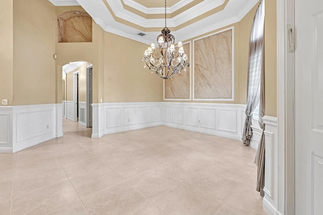 unfurnished dining area featuring ornamental molding, a tray ceiling, and a chandelier