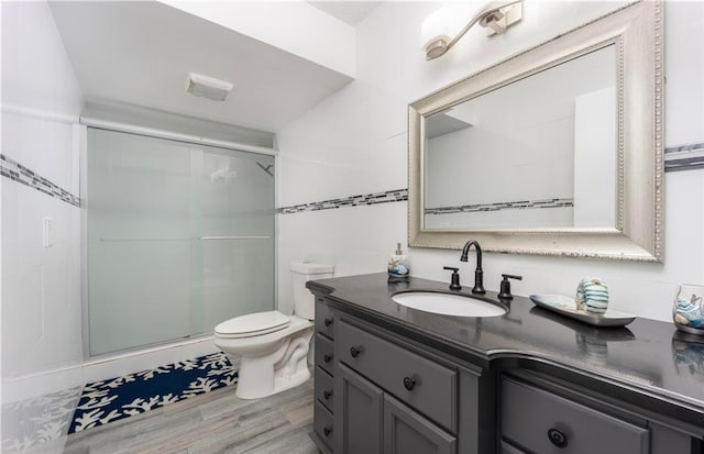 bathroom with vanity, toilet, wood-type flooring, and a shower with shower door