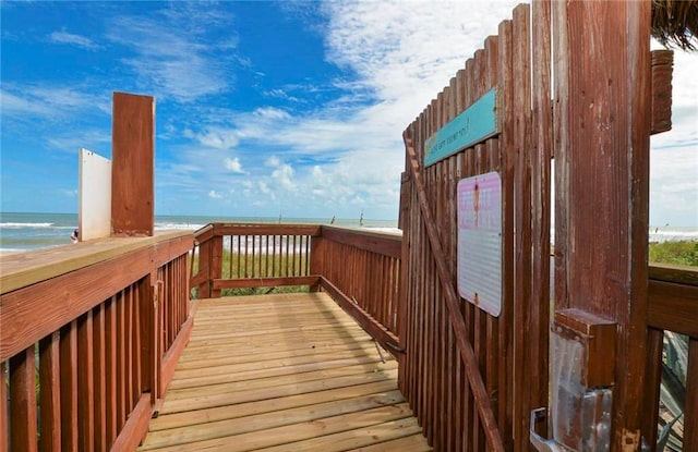 wooden terrace featuring a water view and a beach view