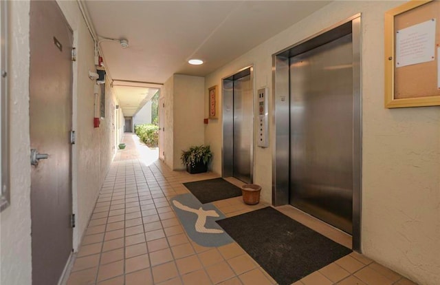 hall with light tile patterned floors and elevator